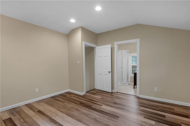 spare room with light wood-type flooring and lofted ceiling