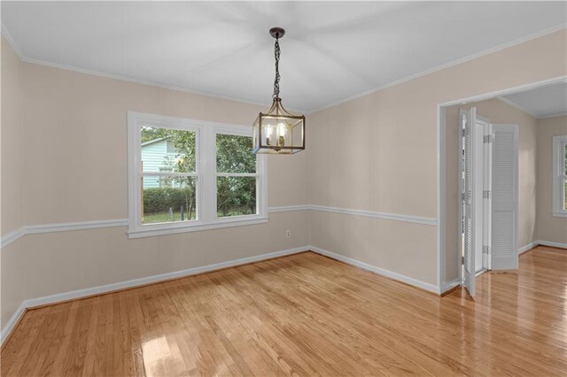 spare room featuring a chandelier, light hardwood / wood-style flooring, and ornamental molding