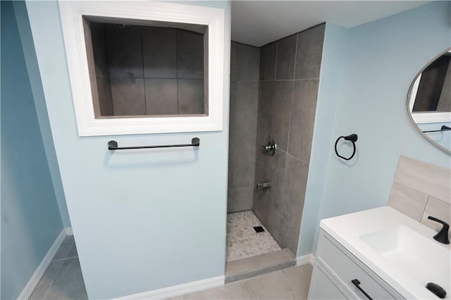 bathroom featuring vanity, baseboards, tile patterned flooring, and a walk in shower