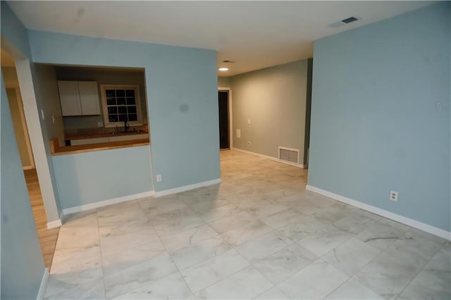 unfurnished room with baseboards, visible vents, and a sink
