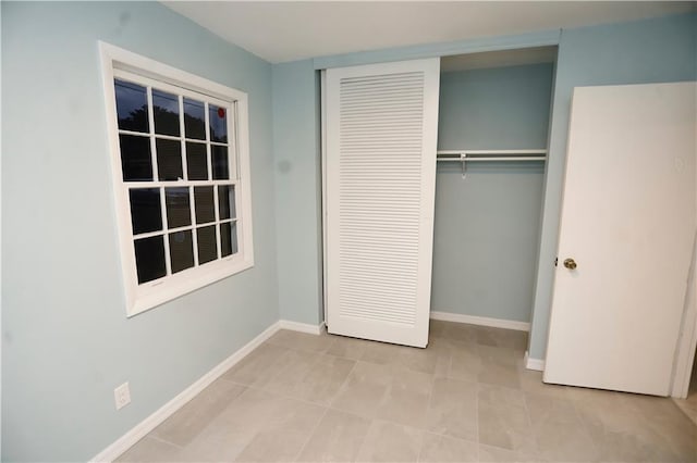 unfurnished bedroom with a closet, tile patterned floors, and baseboards
