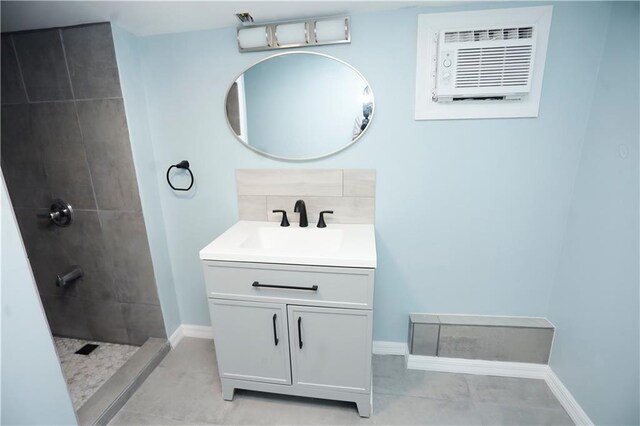 full bathroom with tiled shower, vanity, baseboards, tile patterned flooring, and a wall unit AC