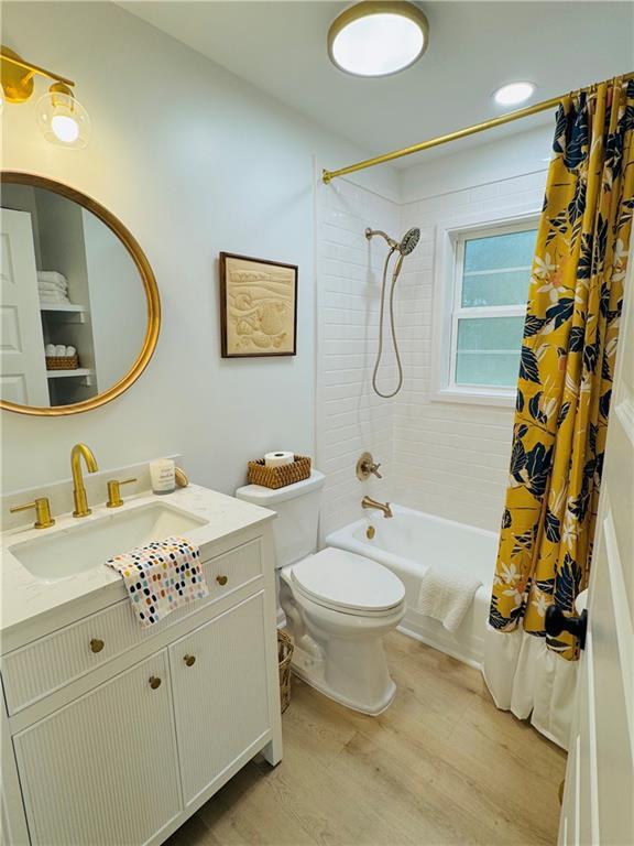 full bathroom with vanity, hardwood / wood-style flooring, toilet, and shower / bath combo