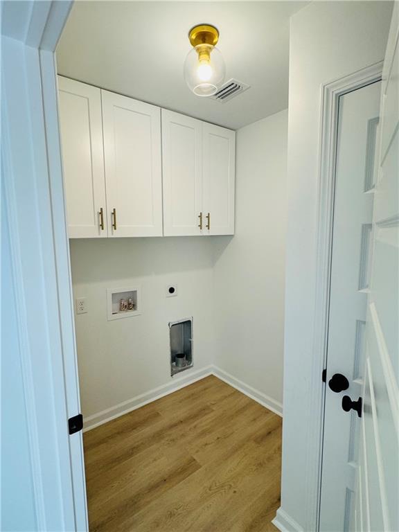 laundry room with cabinets, hookup for a washing machine, light hardwood / wood-style floors, and electric dryer hookup