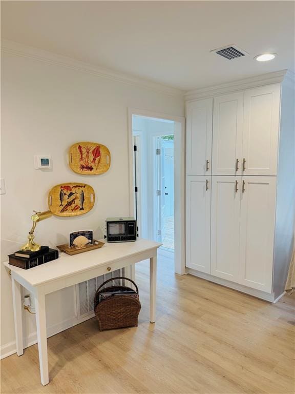 interior space featuring crown molding and light hardwood / wood-style flooring