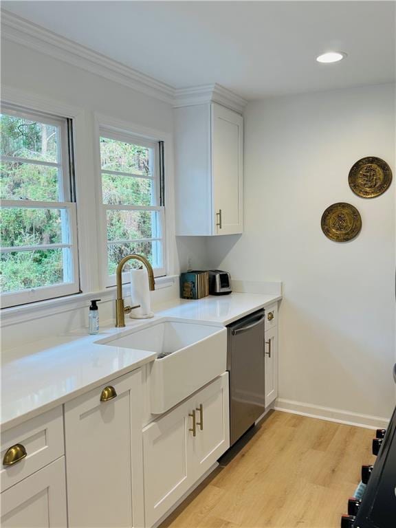 kitchen featuring sink, light hardwood / wood-style flooring, stainless steel dishwasher, a healthy amount of sunlight, and white cabinets