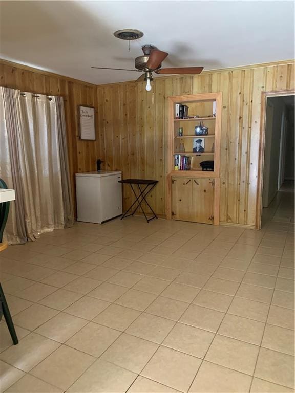 unfurnished room featuring ceiling fan, wooden walls, and light tile patterned floors