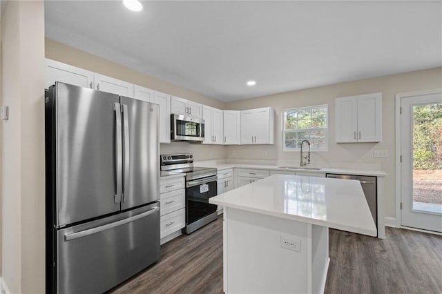 kitchen with sink, appliances with stainless steel finishes, white cabinetry, a center island, and a healthy amount of sunlight