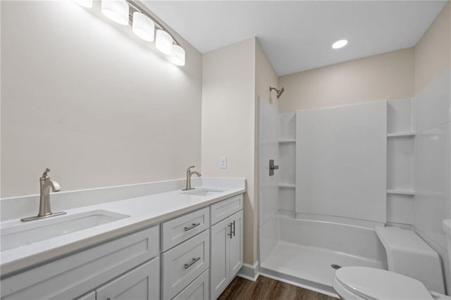 bathroom with hardwood / wood-style flooring, vanity, toilet, and walk in shower