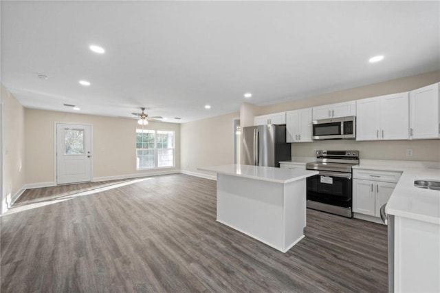 kitchen with white cabinetry, a center island, appliances with stainless steel finishes, dark hardwood / wood-style flooring, and ceiling fan