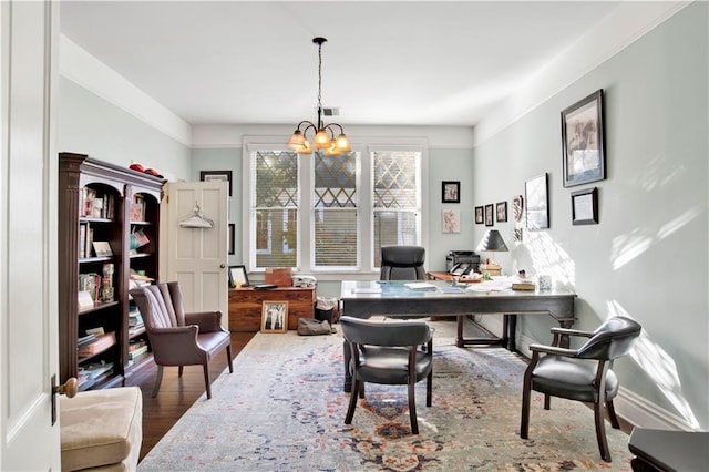 office area with wood-type flooring, ornamental molding, and a chandelier