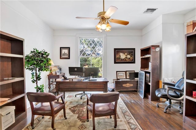 home office with ceiling fan and dark wood-type flooring