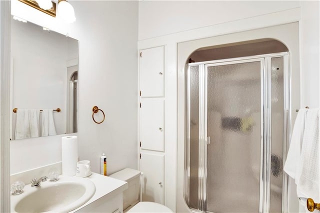 bathroom featuring vanity, toilet, and a shower with door