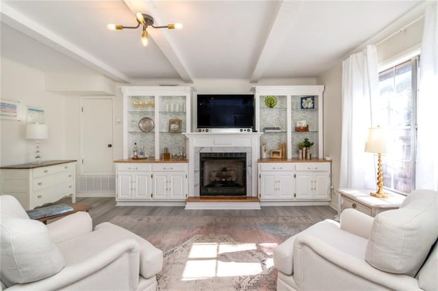 living room featuring wood-type flooring, beam ceiling, and a fireplace