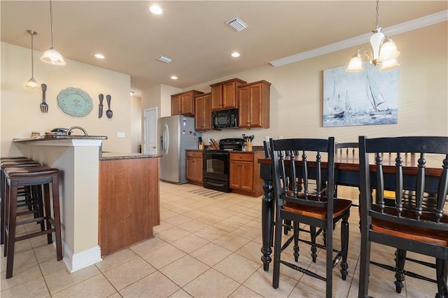 kitchen with black appliances, a peninsula, decorative light fixtures, and brown cabinets