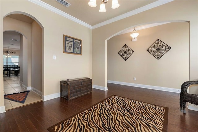 interior space featuring a chandelier, visible vents, crown molding, and wood finished floors