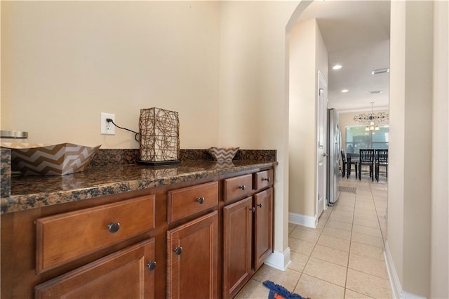 hallway with arched walkways, light tile patterned flooring, baseboards, and recessed lighting