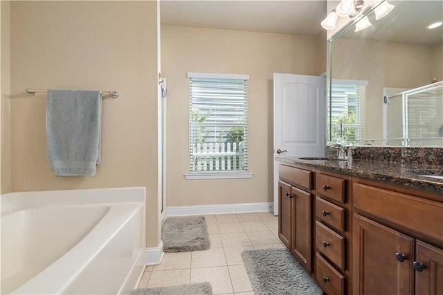 full bath featuring tile patterned flooring, a garden tub, a sink, baseboards, and double vanity