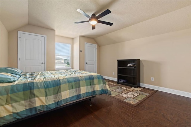 bedroom with lofted ceiling, a textured ceiling, wood finished floors, and baseboards