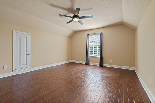 bonus room with baseboards, lofted ceiling, ceiling fan, dark wood-type flooring, and a textured ceiling