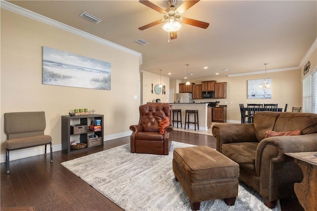 living room featuring ornamental molding, dark wood finished floors, visible vents, and baseboards