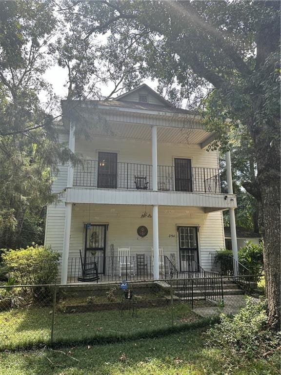 rear view of property featuring a balcony and a porch