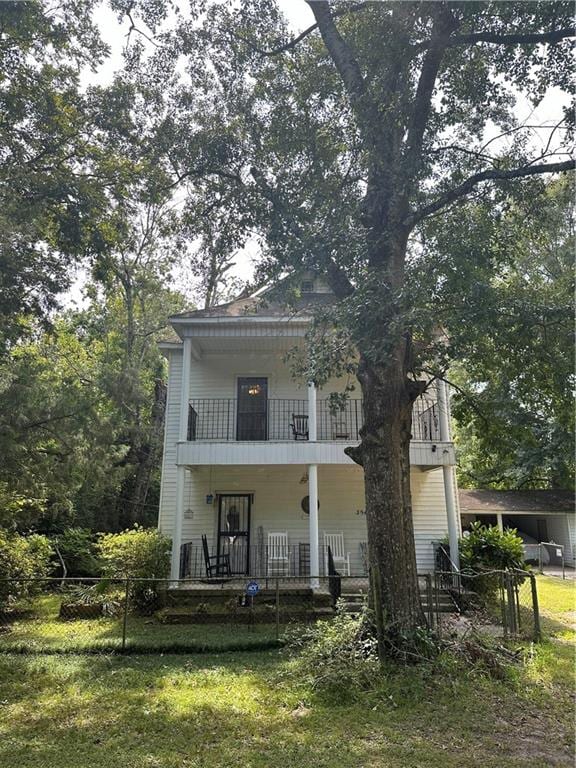 rear view of house with a balcony and a yard