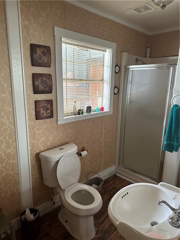 bathroom with hardwood / wood-style floors, toilet, crown molding, and a shower with shower door