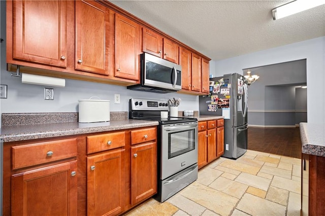 kitchen with a textured ceiling, stainless steel appliances, an inviting chandelier, and light hardwood / wood-style floors