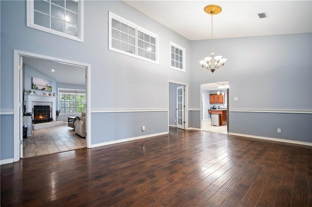 spare room featuring high vaulted ceiling, a chandelier, and dark hardwood / wood-style flooring