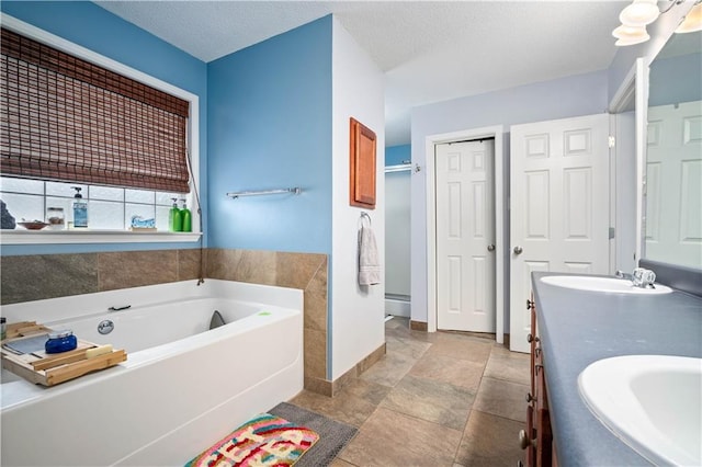 bathroom with vanity, a textured ceiling, a bathing tub, and tile patterned flooring