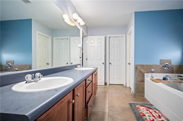 bathroom featuring tile patterned flooring, a bathing tub, a textured ceiling, and vanity