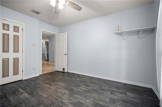 unfurnished bedroom featuring dark wood-type flooring, a textured ceiling, and ceiling fan