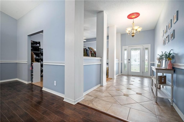 entrance foyer with a textured ceiling, wood-type flooring, and an inviting chandelier