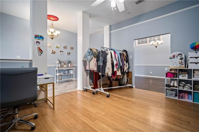 office space featuring ceiling fan with notable chandelier and wood-type flooring