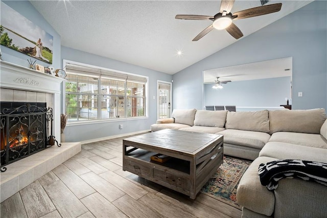 living room featuring light hardwood / wood-style floors, lofted ceiling, ceiling fan, and a tile fireplace