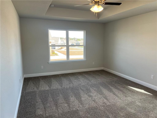 carpeted spare room with ceiling fan and a tray ceiling