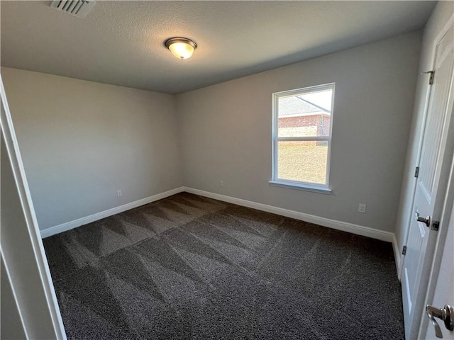 empty room with dark colored carpet and a textured ceiling