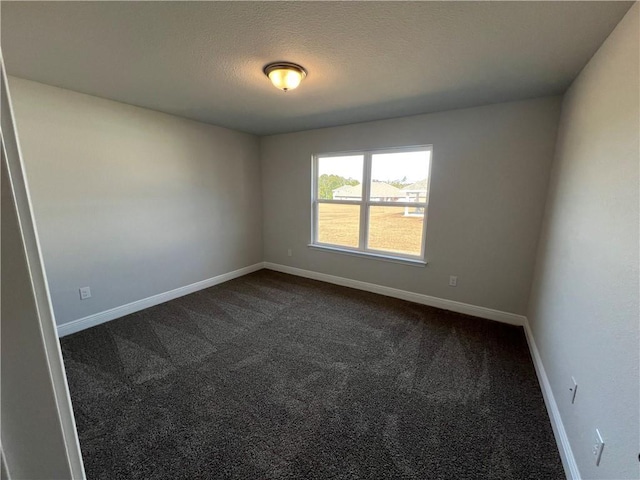 spare room featuring a textured ceiling and dark colored carpet