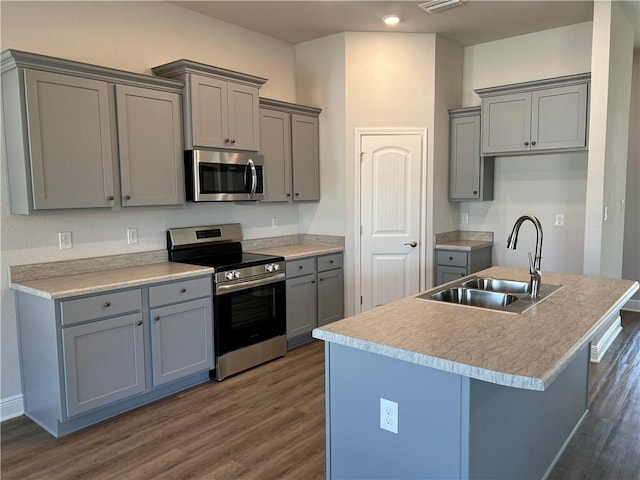 kitchen with sink, a center island with sink, appliances with stainless steel finishes, and gray cabinetry