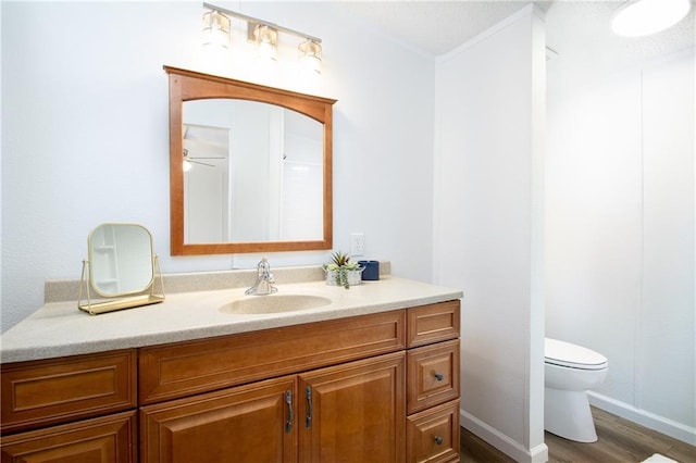 bathroom with wood finished floors, vanity, toilet, and baseboards