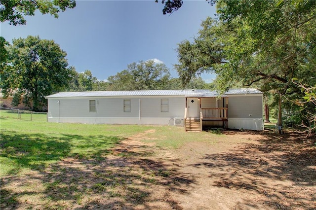 back of house with metal roof and a yard