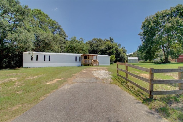 manufactured / mobile home featuring driveway, a front yard, and fence