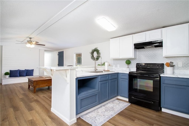 kitchen with a peninsula, blue cabinets, light countertops, under cabinet range hood, and black range with electric cooktop