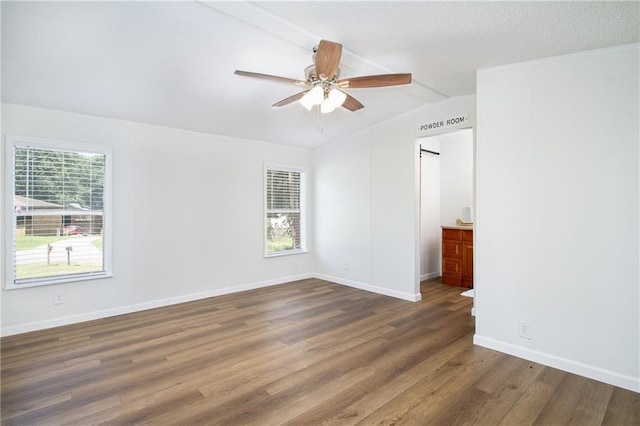 unfurnished room with a ceiling fan, lofted ceiling, baseboards, and wood finished floors