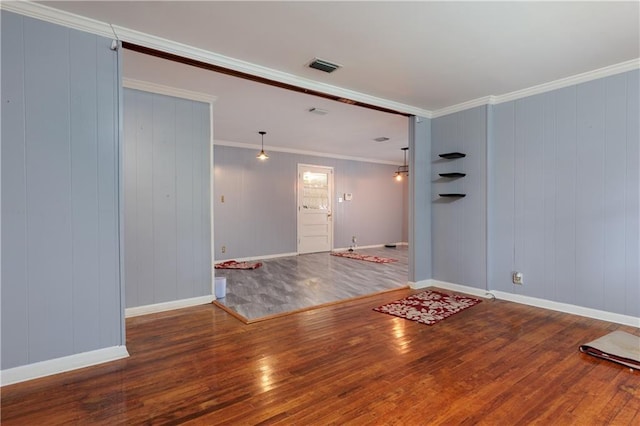 unfurnished room featuring wood-type flooring, visible vents, baseboards, and ornamental molding