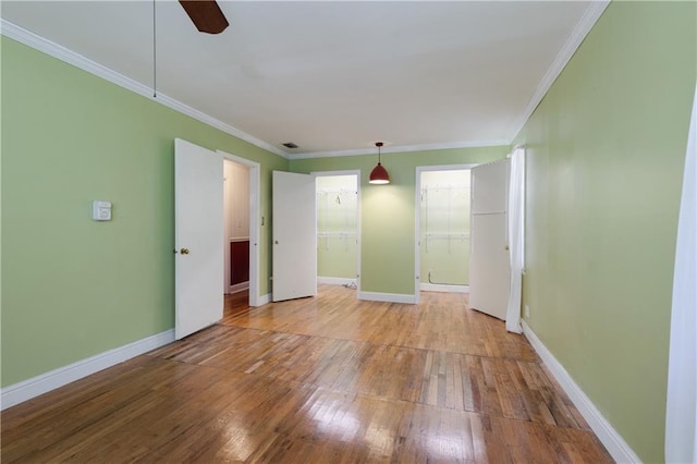 unfurnished room featuring wood-type flooring, baseboards, and ornamental molding
