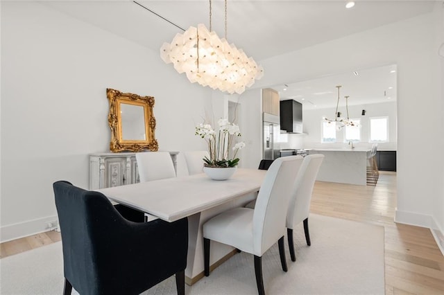 dining area with an inviting chandelier and light hardwood / wood-style flooring