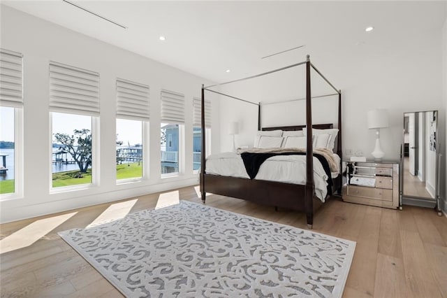 bedroom with a water view and light hardwood / wood-style floors