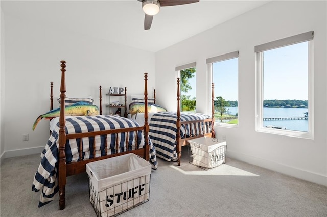 carpeted bedroom featuring a water view and ceiling fan